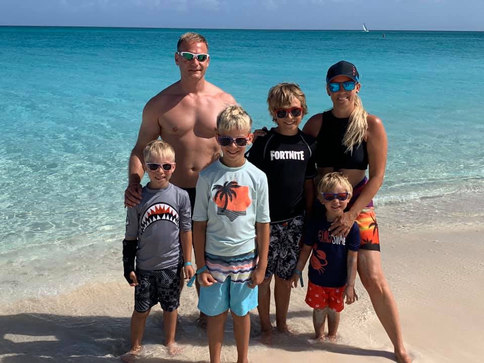 A family of five stands on a sandy beach on a sunny day in Turks and Caicos.