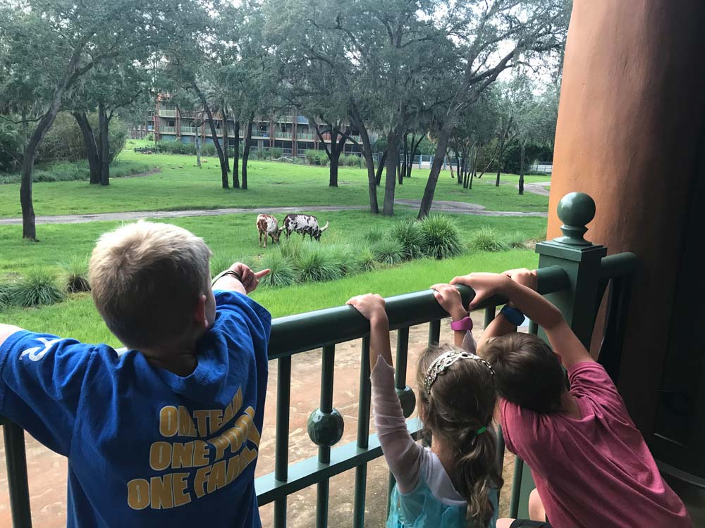 Three kids standing on balcony loking at animals at hotel in Disney World