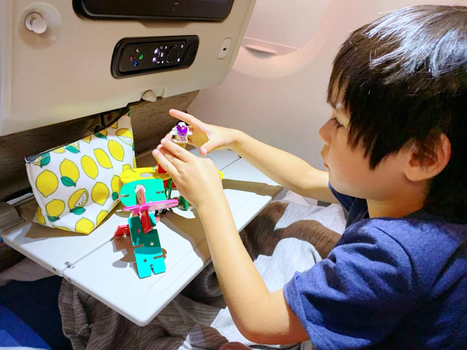 Small boy playing with toys on an airplane, bringing new toys is a great way to keep kids entertained while traveling.
