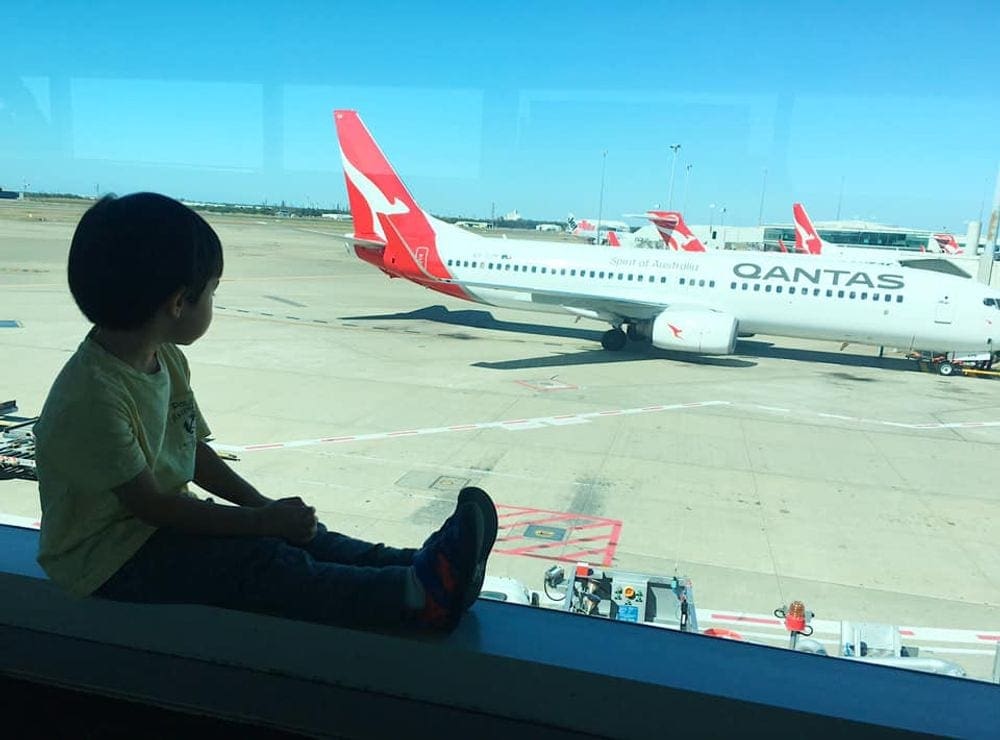 Small child looks out the window in an airport viewing the planes outside.