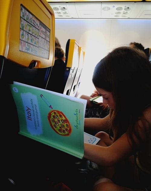 Small girl works through a workbook on an airplane.