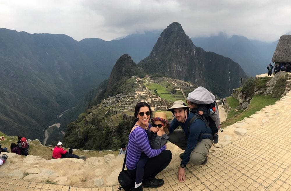 A family of four stands in front of an expansive view of Machu Picchu in Peru, one of the best places in South America with kids.
