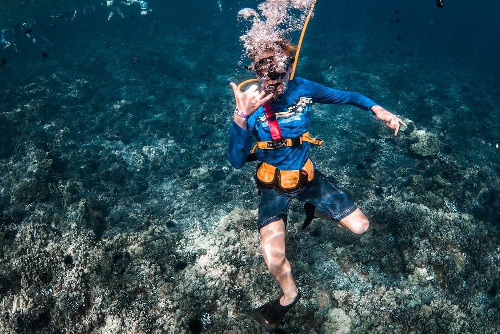 A scuba diver gives the "hang ten" symbol while underwater near Maui, one of the best vacation spots in the US to impress teens and tweens.