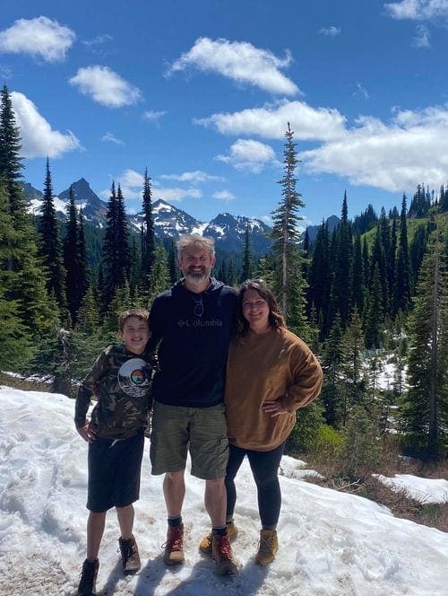 A family of three stand in the snow at Mt. Rainier National Park.