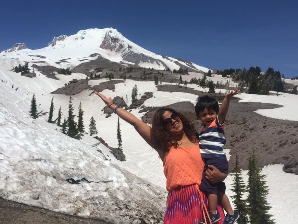 Mom and son stand excitedly in front of Mt. Rainier covered in snow.