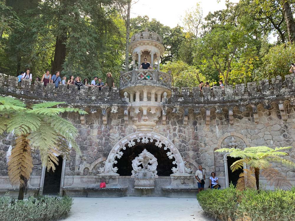 Tourists stand high on a balcony area overlooking the Gardens of Quinta da Regaleira in Portugal.