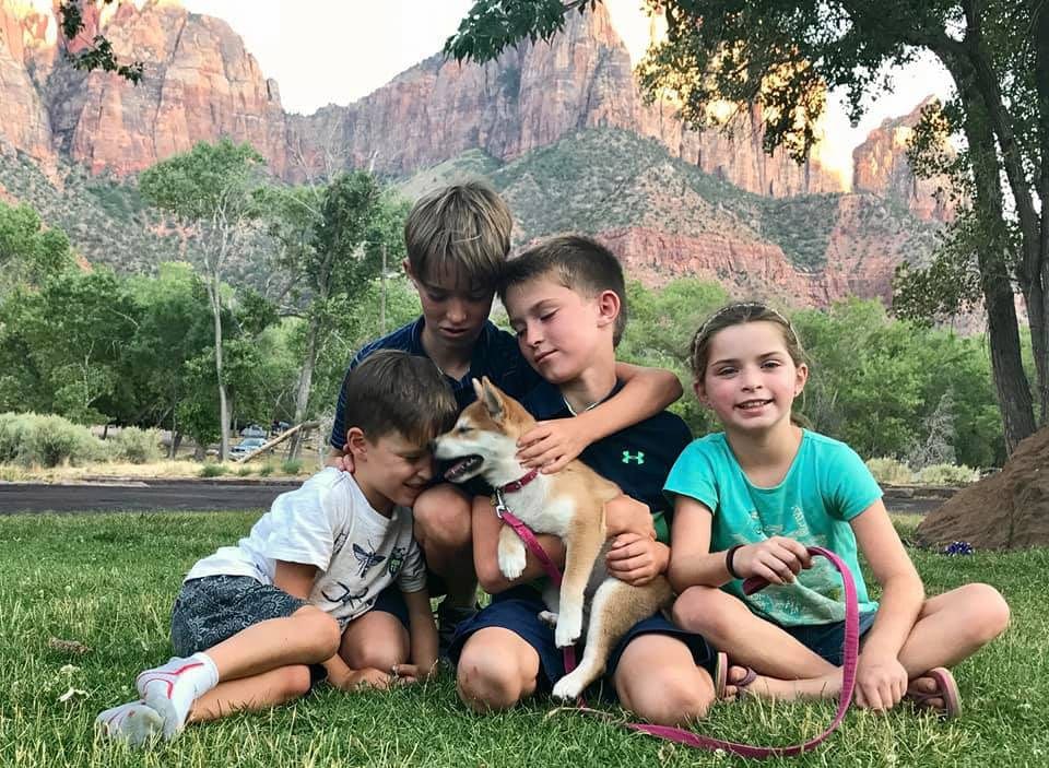 Four kids cuddle with a puppy amoung the cliffs of Sedona, Arizona.