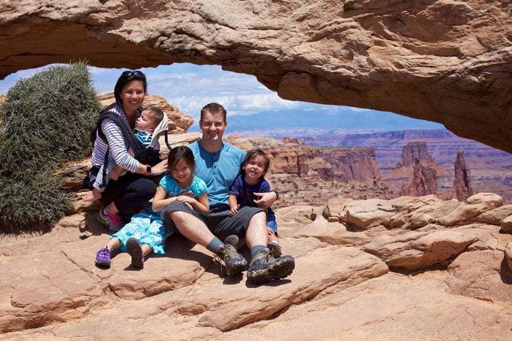 A family of five poses amoung large rocks at Canyonland National Park.
