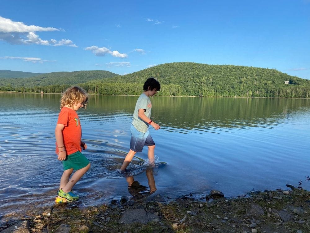 Two young children wade ankle deep in the crystal clear waters of Cooper Lake Reservoir.