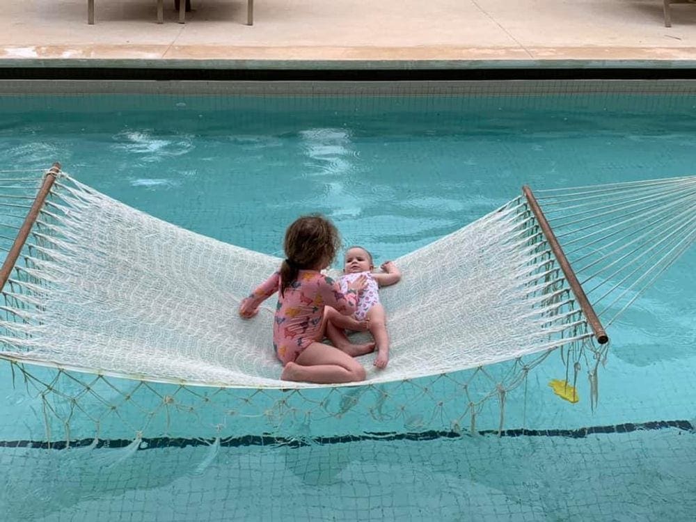 A young girl and her baby sister relax on a hammock over the pool at the Finest Playa Mujeres in Cancun.