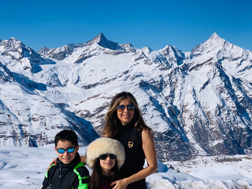 A mom stands with her two children in a snow-covered mountain landsape. Building courage and self-esteem is one of the greatest benefits of traveling with kids.