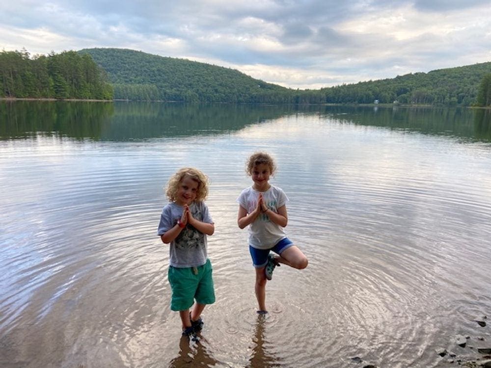 Two kids stand in mountain pose within a stunning lake in the Catskill Mountains.
