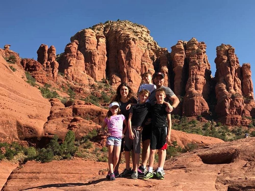 A family of six stands proudly in front of Sedona's iconic red rocks after hiking in the desert.