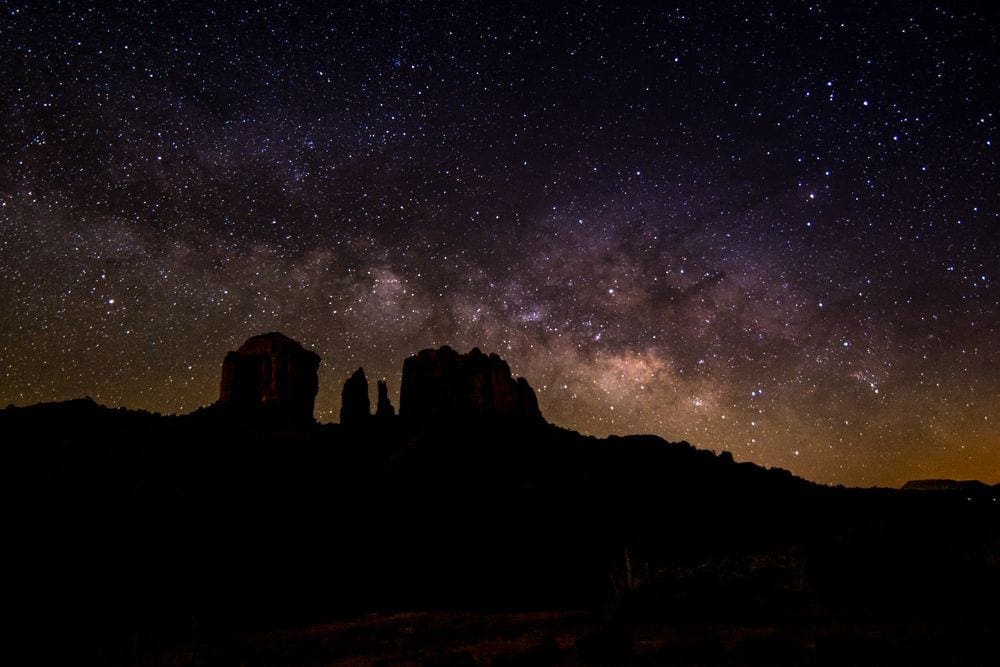 A perfect night sky highlights the shadows of the iconic Sedona red rock formations with brilliant stars dotting the sky.