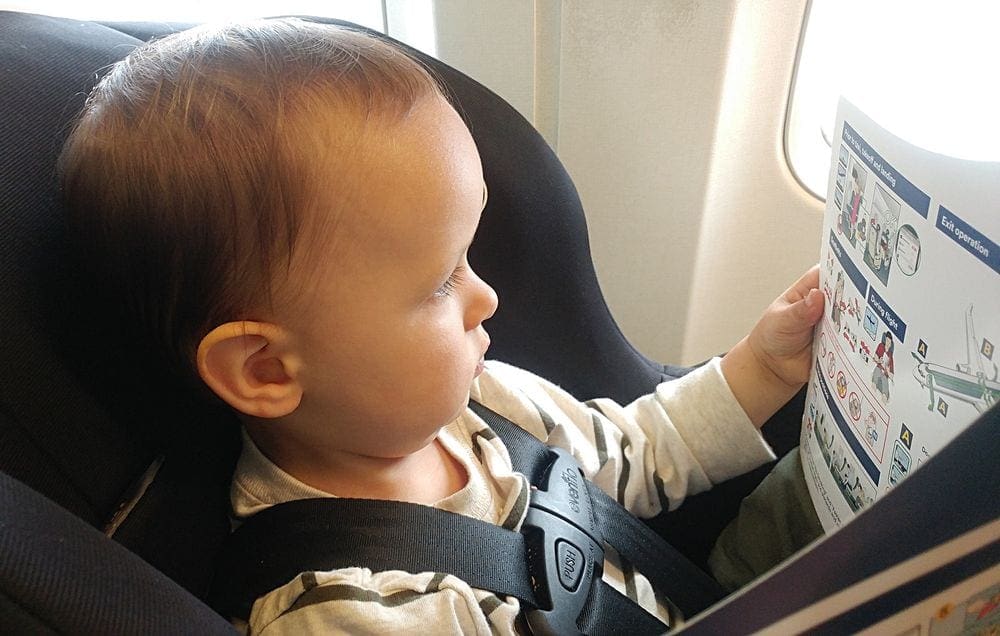 An infant looks at the in-flight safety manual on one of the best airlines for kids