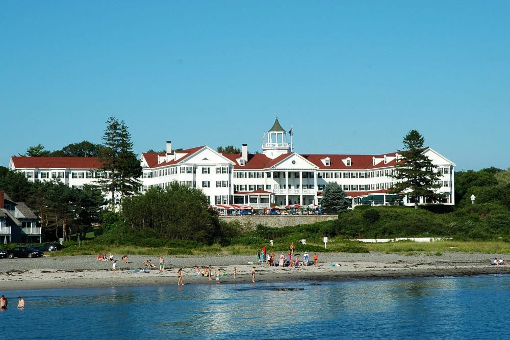 The front view of the Colony Hotel featuring it's iconic pillars, red roof, and ocean-side view.