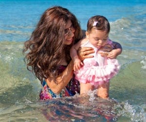 A mom splashes in the water with her infant daughter in Antigua.