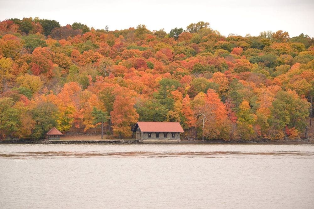 A boat house sits along the Hudson River on a glorious fall day.
