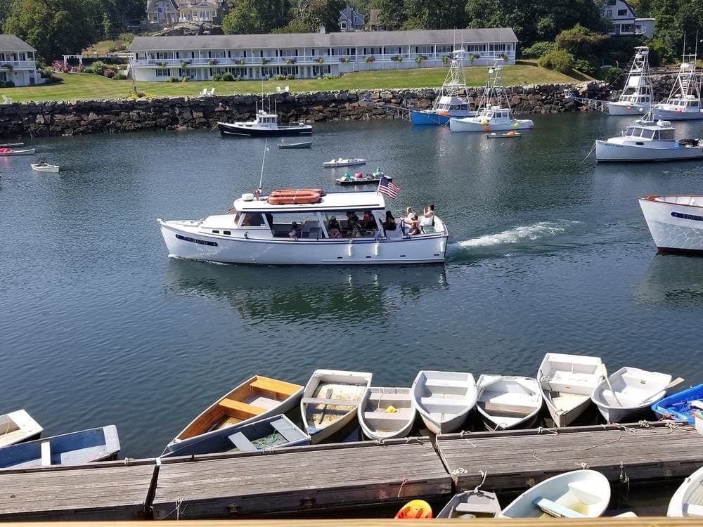 A ship carring tourists goes out to see, while other small boats are tied along the harbor in Ogunquit, one of the best weekend getaways near Boston for families.