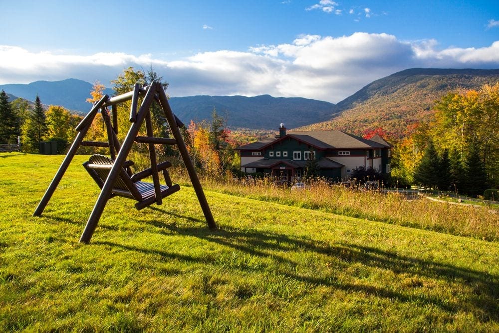 A swing sits on a beautiful grassy hill overlooking the grounds of Smuggler's Notch Resort.