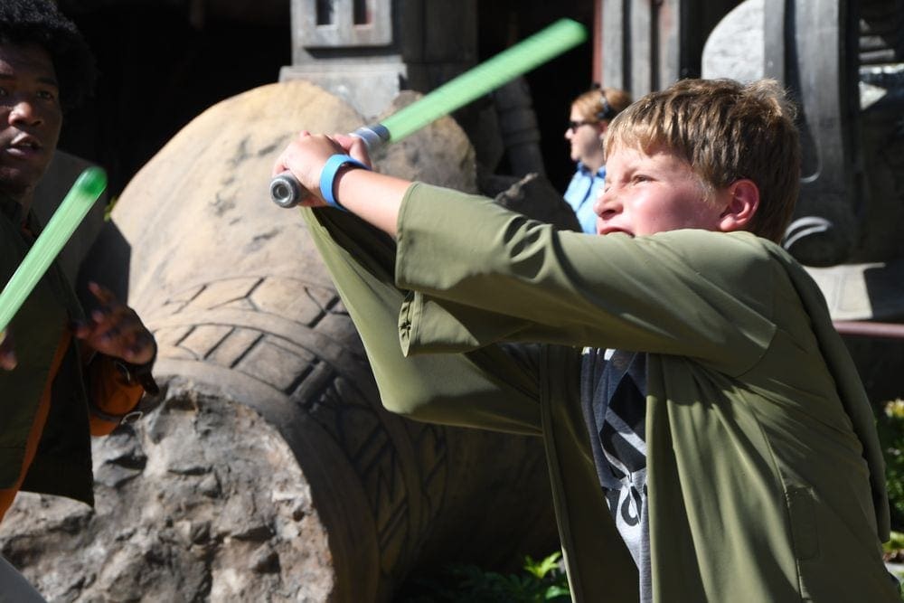 A young boy dressed as a Jedi swings a lightsaber at Disney Hollywood Studios.