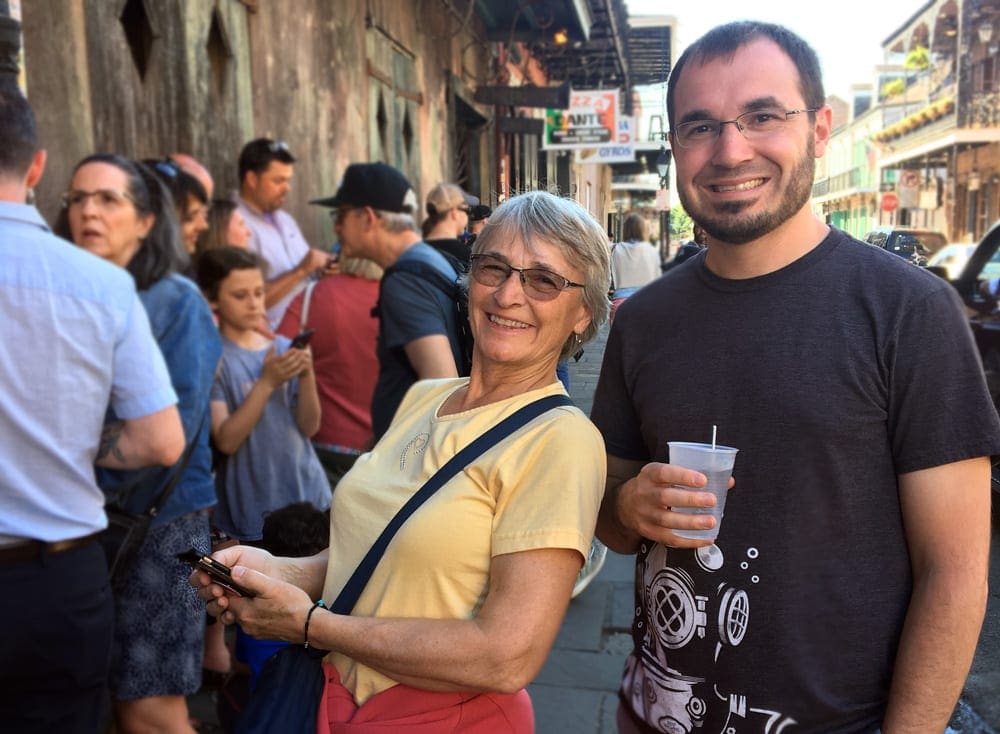 A man holding a drink poses with his mom outside of Preservation Hall before a show.