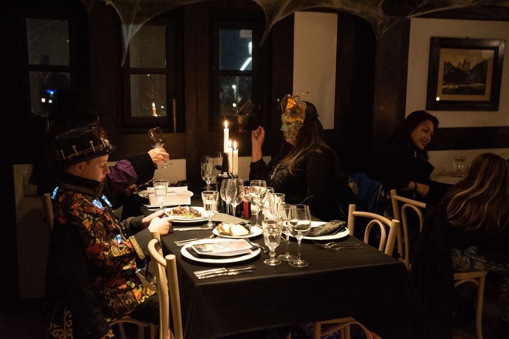 A teenager and his parents, all wearing costumes, enjoy a Halloween-inspired meal in Bran Castle.