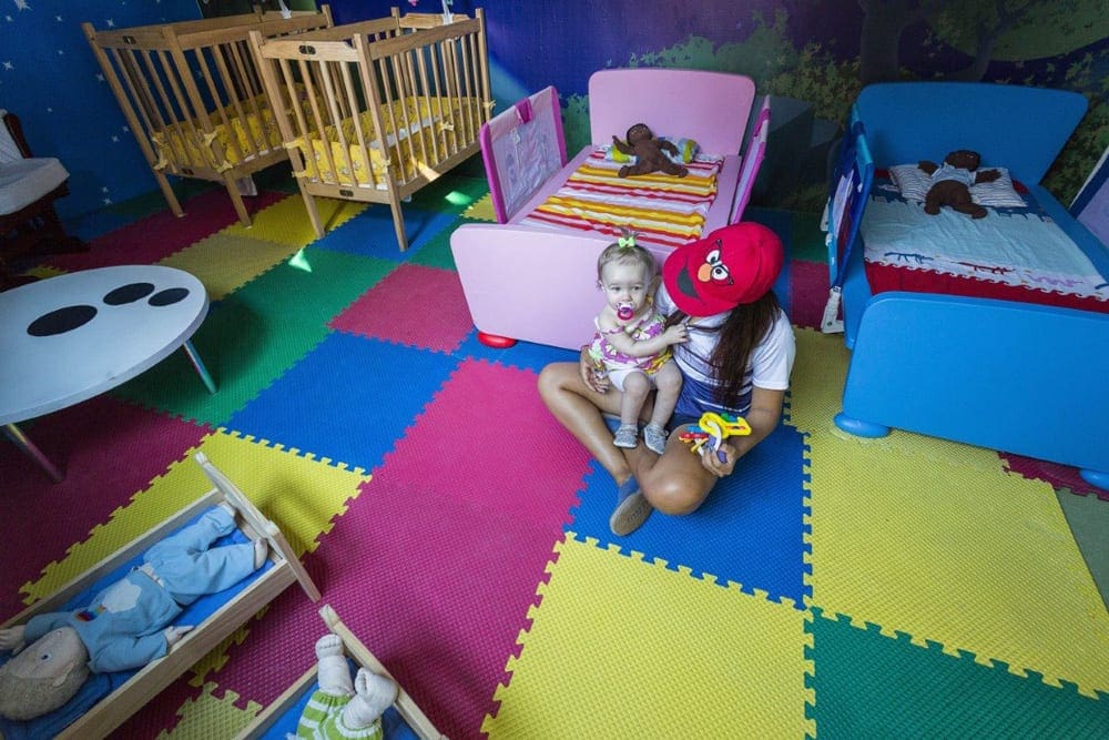 An infant sits with a child-care provider within the baby club at Grand Palladium Vallarta Resort & Spa.