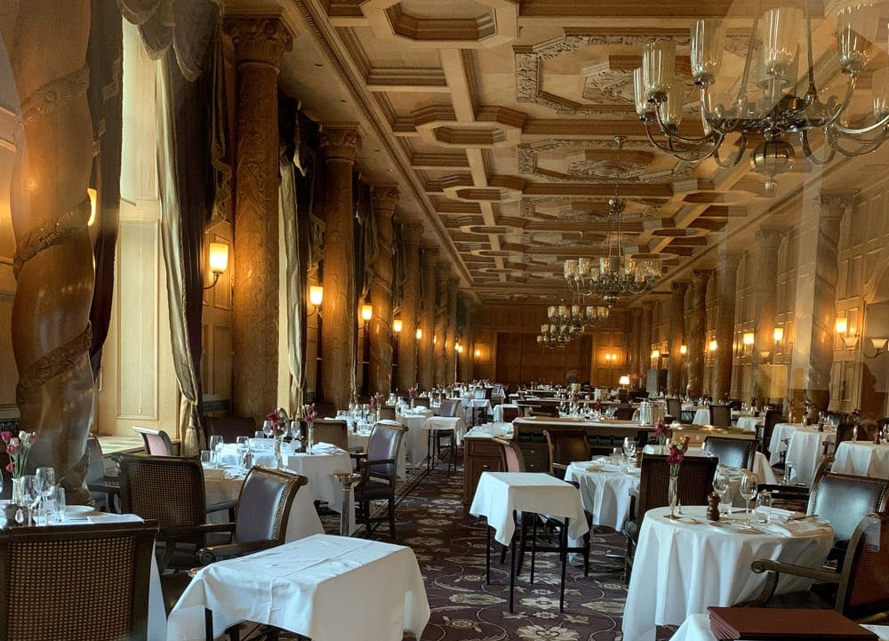 The inside of the Grant Resturant of Suvretta House, featuring high-end chairs, tables, and ambiance.