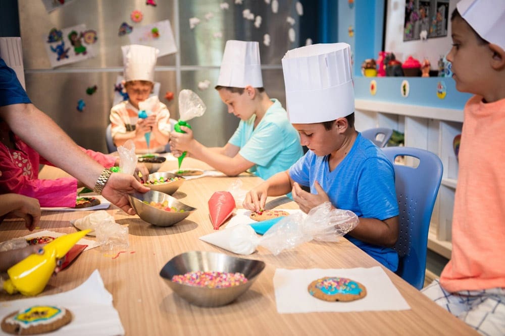 Four kids surround a table decorating cookies at the on-site kids club at JW Marriott Marco Island, one of the best family resorts in Florida.