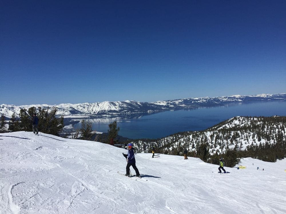 A young boy skis down a hill with Lake Tahoe in the distance.