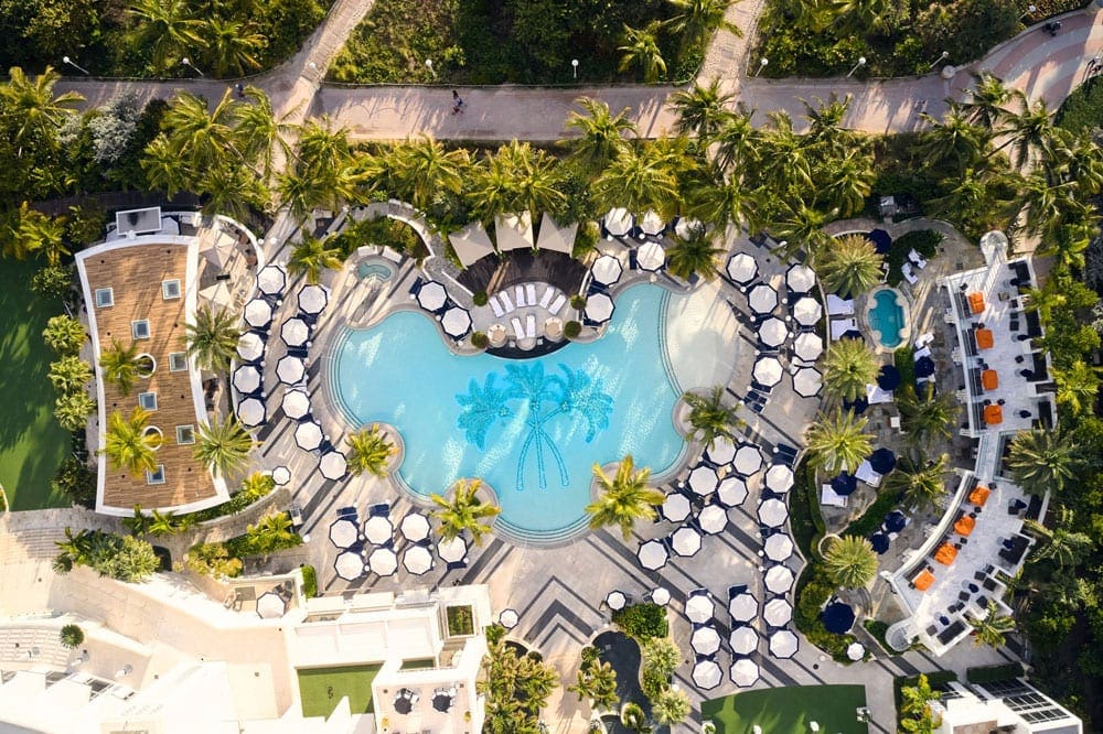 An aerial view of the Lowes Miami Beach Hotel, featuring a pool, exansive grounds, and cabanas.