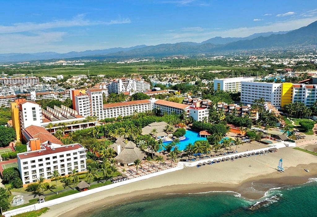 An aerial view of Meliá Puerto Vallarta, featuring a pristine beach and resort grounds.