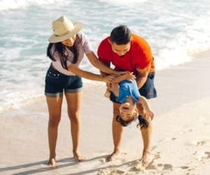 A family of three plays on the beach together, while staying at one of the best resorts in Mexico with a baby club.