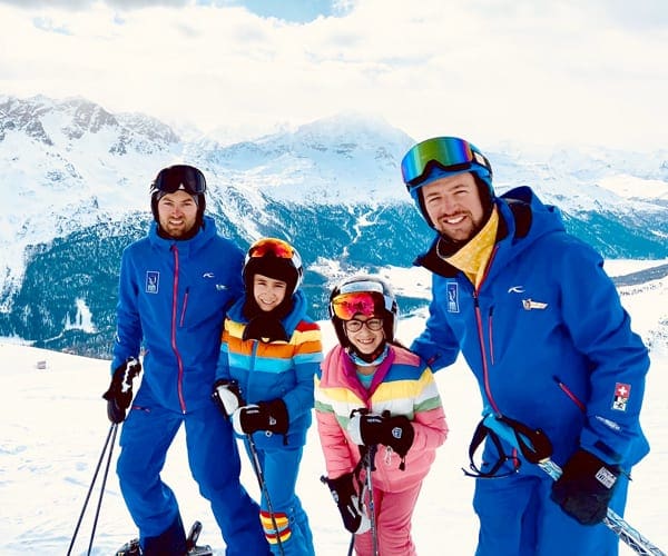 Two kids stand with ski instructors, while skiing in St. Moritz.