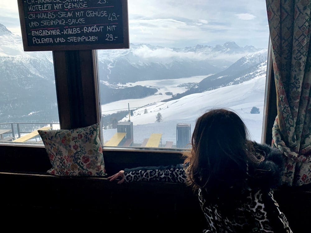 A young girl looks out a windown on a snowy Swiss landscape from a table at Trutz.