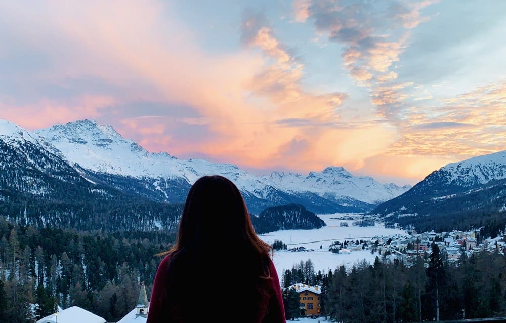 A woman looks out on a sweeping Swiss landscape during the winter.