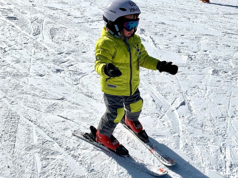 A young boy wearing a large yellow coat skis on a trail at Shawnee Resort, one of the best places to ski in Pennsylvania with Kids