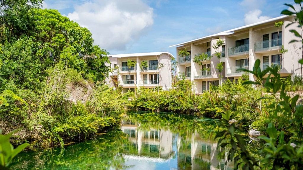 A view of a river within the Andaz Mayakoba Resort Riviera Maya, one of the best resorts in Playa del Carmen, with hotel buildings in the background.