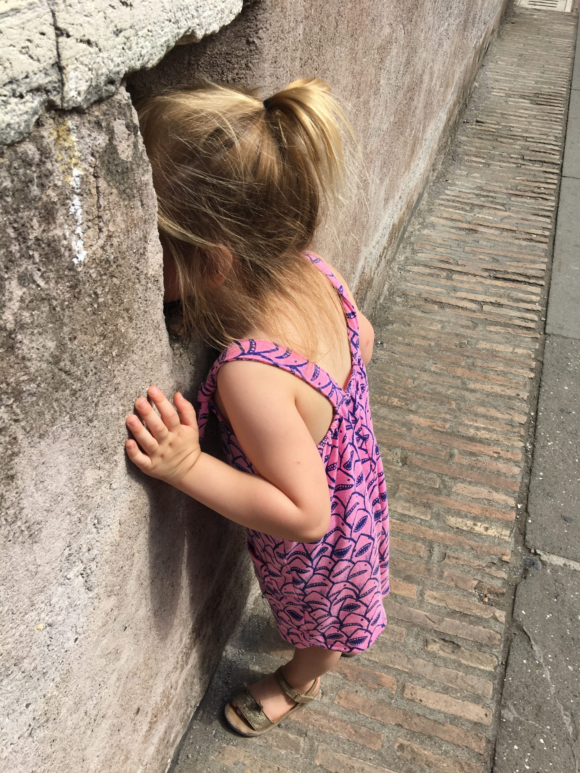 A young girl peaks out a archer's station at Castel Sant'Angelo, one of the best things to do Rome with toddlers.