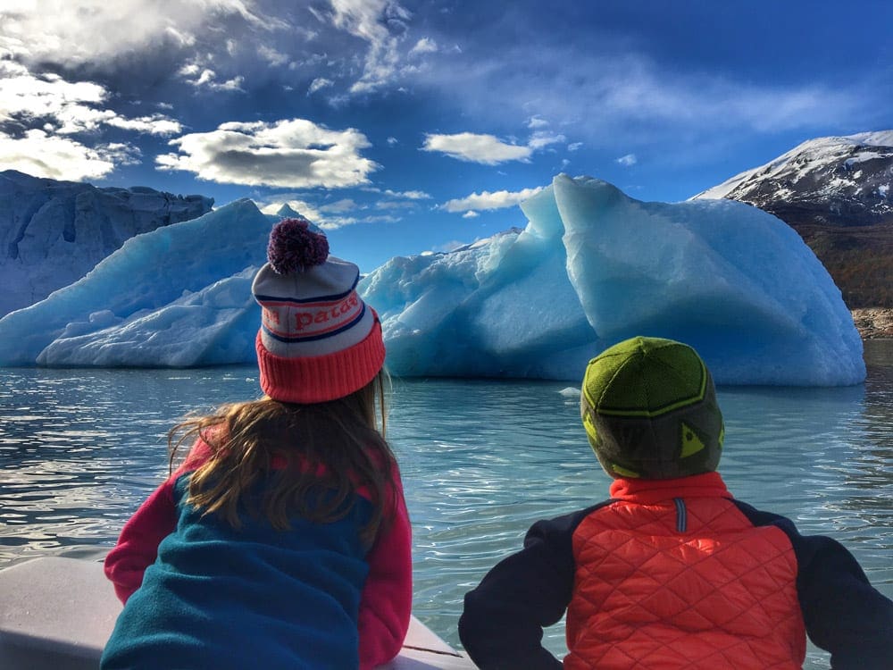 Two young kids wearing warm clothes look at glaciers within Patagonia, one of the best places in South America with kids.
