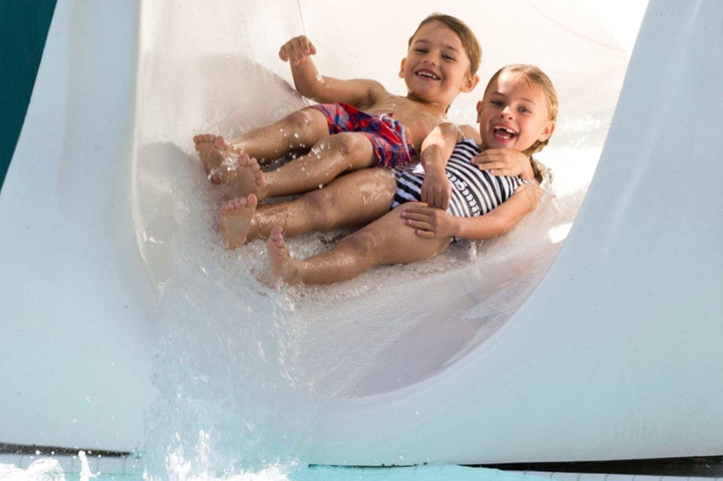 Two kids gleefully slide down a waterslide at Fontainebleau Miami Beach.