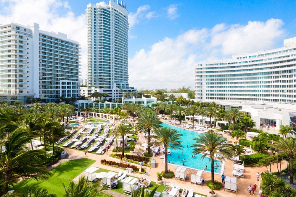 An aerial view of Fontainebleau Miami Beach, ones of the best family-friendly hotels in Miami, featuring palm trees and a turquois pool.