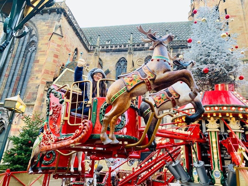 A young girl rides a magical ride in Europe at a Christmas Market.