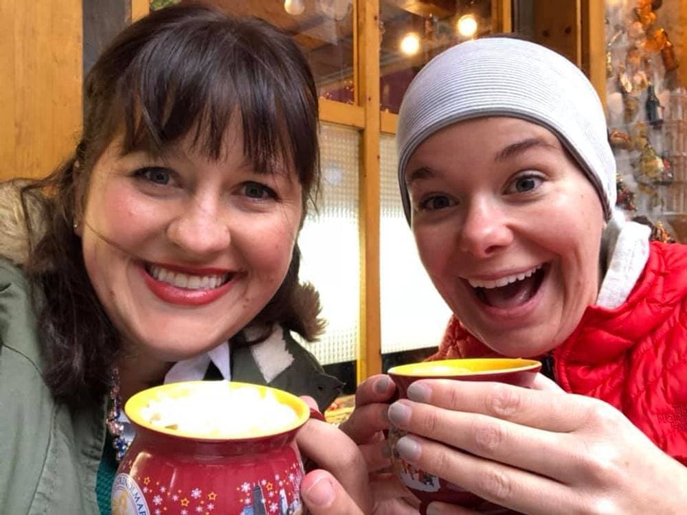 Two women hold coffee mugs with warm beverages at the Christmas Market in Chicago, IL.