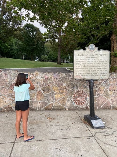 A young girl takes a picture of a historical marker at Graceland.