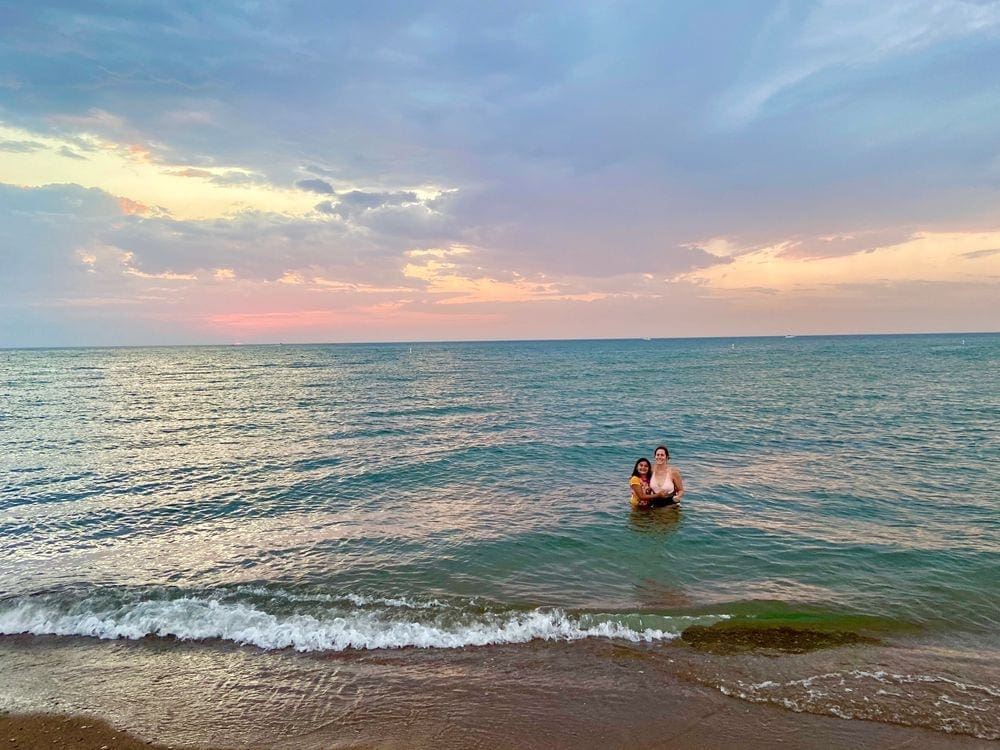 A young girl and her mom swim in Lake Michigan, one of the best places to visit in Michigan with kids.