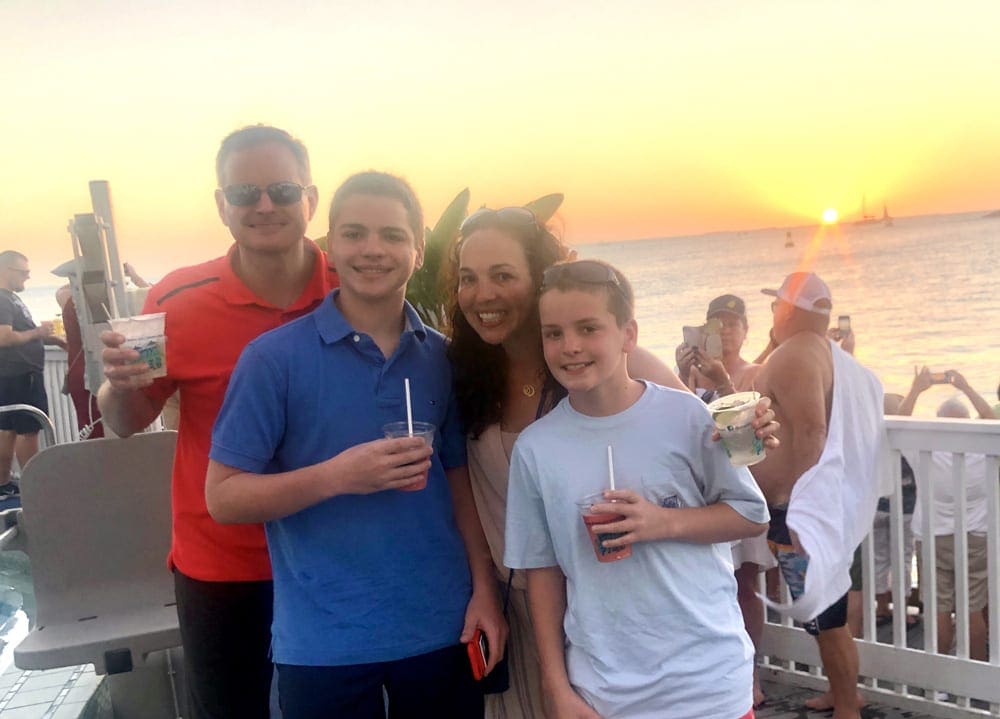 Family posing together with drinks in-hand in front of a Florida sunset.