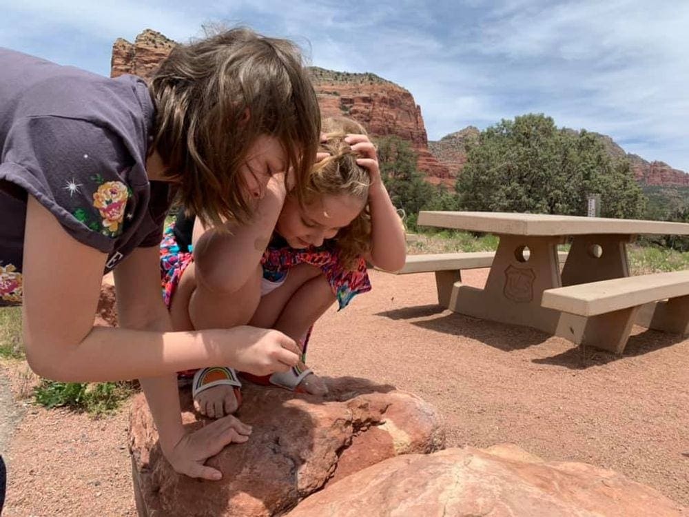 Two kids inspect a rock, while exploring a hiking trail near Sedona.