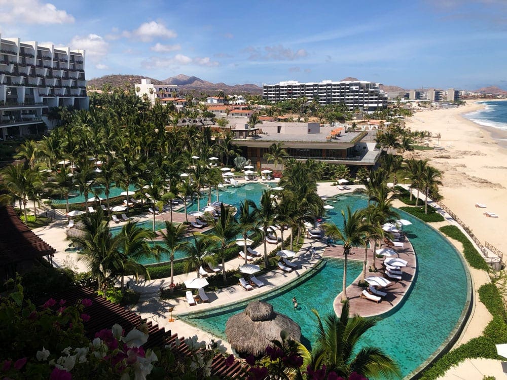 An aerial view of Grand Velas Los Cabos, featuring several pools and a sandy ocean-side beach.